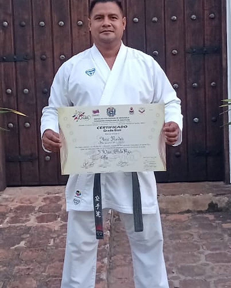 El Sensei José Rondón, en kimono y cinturón negro, sostiene su certificado de grado Dan
